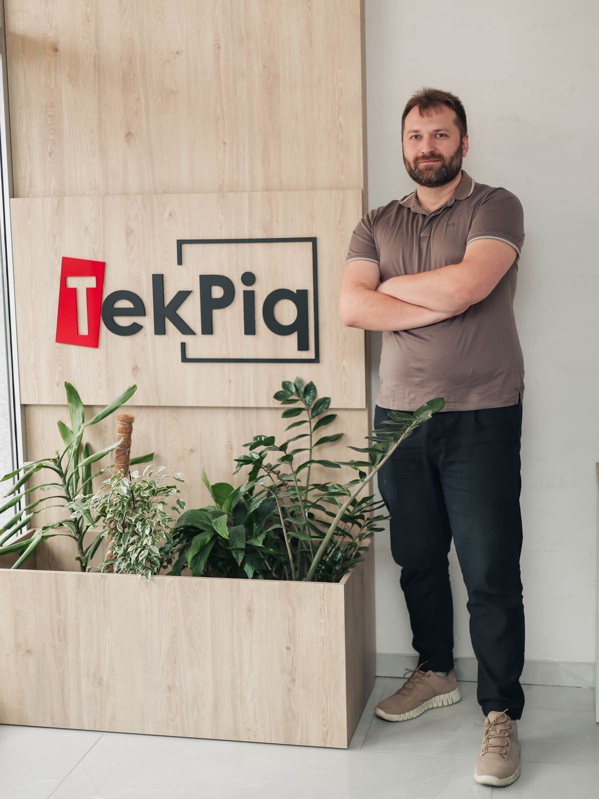 En utvecklare på TekPiq bredvid logoväggen på TekPiqs kontor
