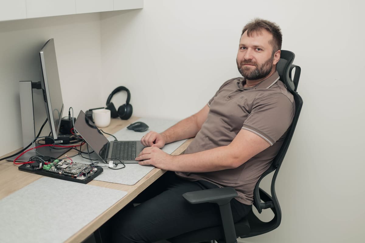 Ein TekPiq-Entwickler am Schreibtisch mit Embedded-Platine, Laptop und Monitor