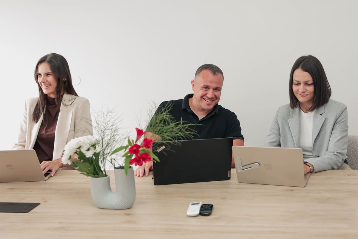 Drei TekPiq-Teammitglieder lachen während eines Meetings am Konferenztisch im Büro